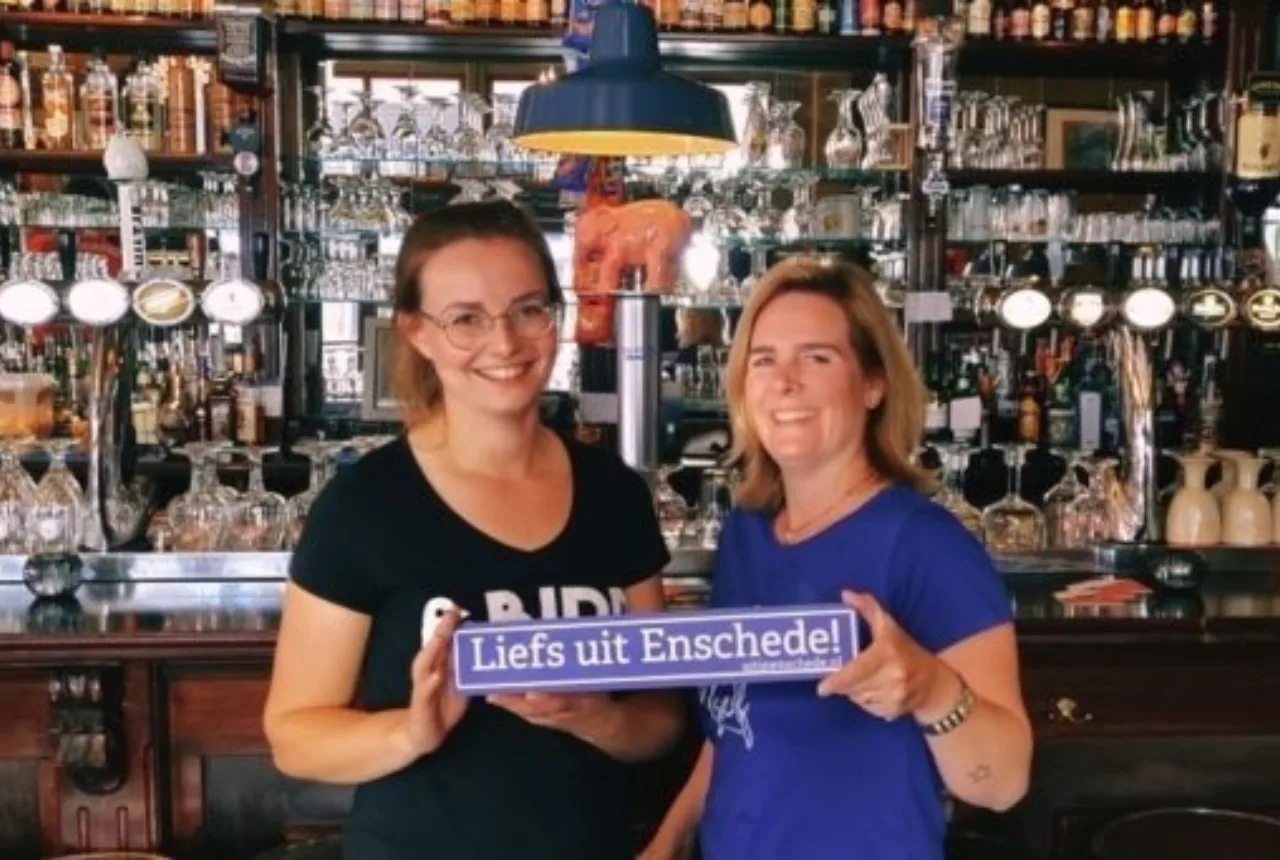 Personeel met een bordje van Liefs uit Enschede bij Proeflokaal België - Uit in Enschede